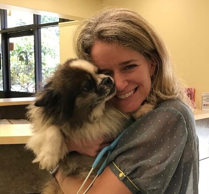 Smiling team member hugging a fluffy dog at Shiloh Veterinary Hospital